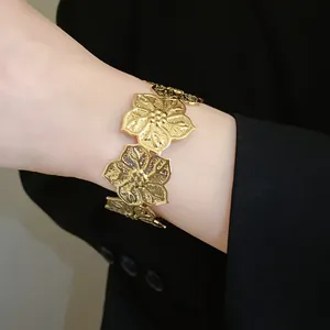 Close-up of elegant gold textured flower cuff bracelet worn on wrist for fashion