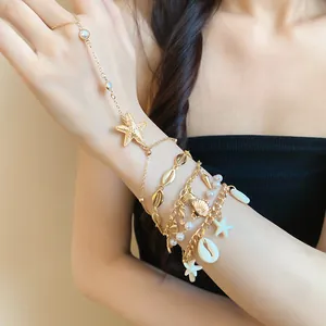 Close-up of bohemian gold hand harness featuring delicate starfish and shell charms