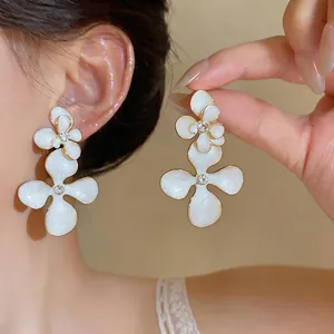 Elegant vintage white enamel flower stud earrings with sparkling rhinestone center detail