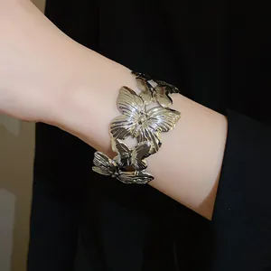 Macro view of a silver metallic cuff bracelet featuring detailed wrinkled butterfly charms.