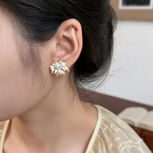 Close-up detail of a white chamomile flower stud earring worn by an elegant model.
