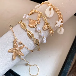 Detail of Bohemian gold-tone charm bracelets with sea shells, starfish, and pearls.