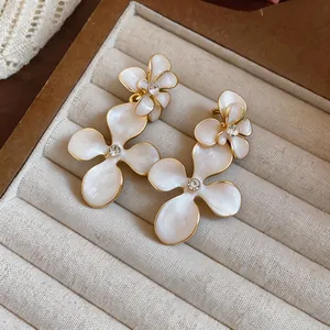 Macro view showing the exquisite white enamel petals and rhinestone center of flower earrings