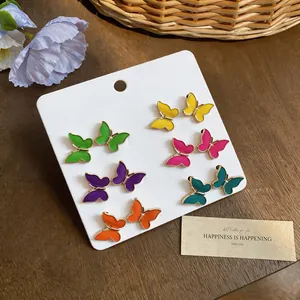 Juego de seis pares de pendientes de mariposa coloridos con elegantes detalles dorados.