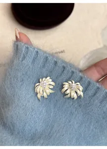 Close-up detail showing elegant chamomile flower earrings with crystals on blue mohair