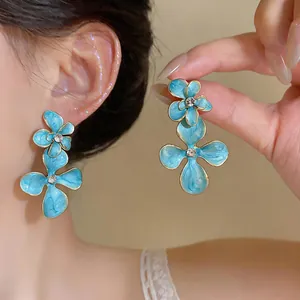 Close-up detail of vintage sky blue enamel flower earrings with central rhinestones.
