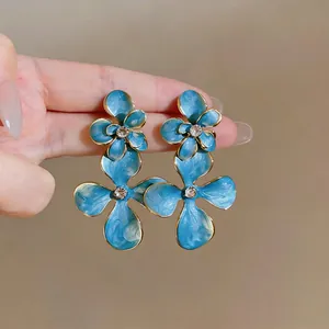Close-up of vintage blue enamel flower earrings with sparkling rhinestone centers