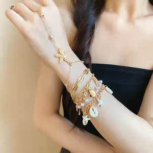 Detail of bohemian gold hand harness with starfish, cowrie shells, and pearls on model.