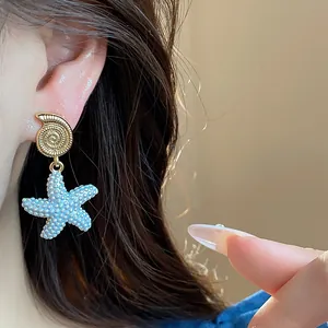 Detalle de un pendiente de estrella de mar y concha con baño de oro de 18k y textura azul