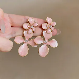 Detailed macro of vintage-style pink enamel flower earrings with sparkling rhinestone center