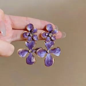 Macro view of vintage style purple enamel flower earrings with central rhinestones