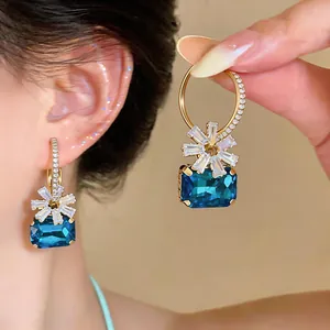 Detailaufnahme luxuriöser geometrischer blauer Zirkon-Ohrringe mit weißen Kristallblumen-Akzenten