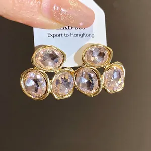Elegant gold-plated stud earrings featuring faceted light pink crystals on a display card