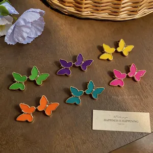 Primer plano de pendientes de mariposa de esmalte colorido en tonos de verano