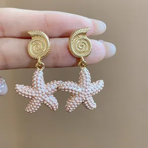 Primer plano detallado de pendientes de caracola dorada y estrella de mar rosa