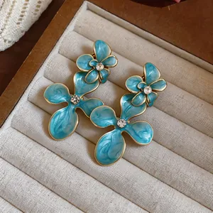 Detailed close-up of vintage blue enamel flower earrings with sparkling rhinestone center