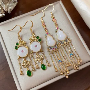Detailed close-up of vintage gold-plated gourd earrings featuring white jade-style stones.