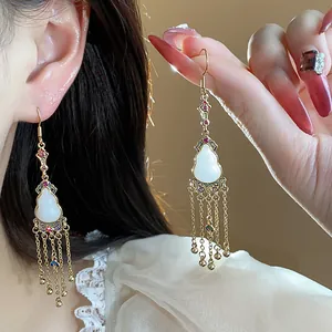Detailed view of gold-plated gourd earrings with white jade-like stone and tassels