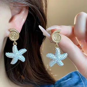 Detalle macro de pendientes de gota de estrella de mar bañados en oro de 18 quilates