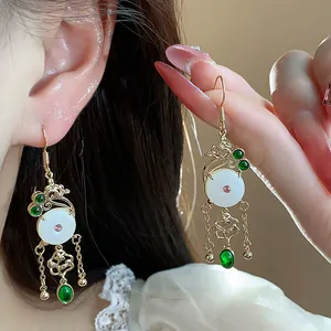 Close-up of luxury 14K gold plated drop earrings with white jade-like stones and gems