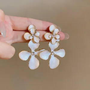 Vintage palace style white enamel floral earrings with crystal center detail view