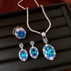 Elegant jewelry set with oval blue zircon pendant necklace, matching ring, and earrings.
