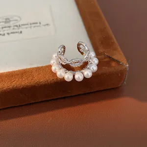 Primer plano detallado de un elegante pendiente de presión doble con perlas y circonitas.