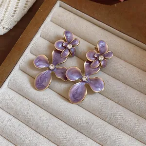 Detailed close-up of vintage purple enamel flower earrings with central crystal inlay.