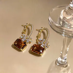 Elegante goldene Creolen mit braunen Edelsteinen und Kristallblumen-Details im Nahaufnahme