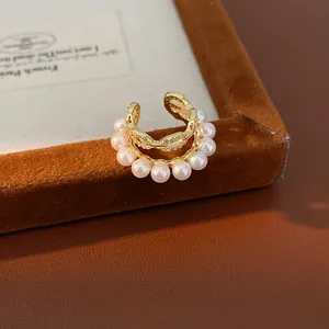Primer plano de un elegante brazalete de oreja dorado de doble capa con perlas y circón.