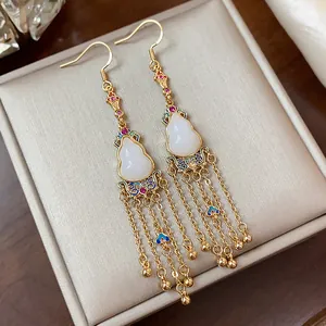 Macro view of 14K gold plated gourd tassel earrings featuring elegant white jade-like stones