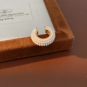 Vista detallada de un manguito de oreja dorado de lujo con doble fila de perlas