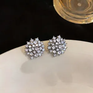 Eleganti orecchini a perno in argento con zirconi scintillanti su un piatto di ceramica bianca