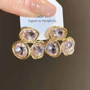 Close-up of elegant gold earrings with oval pink crystals on a white tag