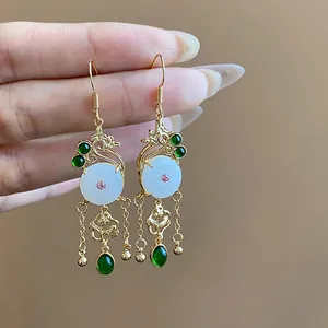 Detailed macro view of 14K gold-plated earrings with white jade and green stones