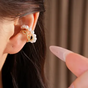 Primer plano detallado que muestra un ear cuff de doble capa con perlas y circonitas