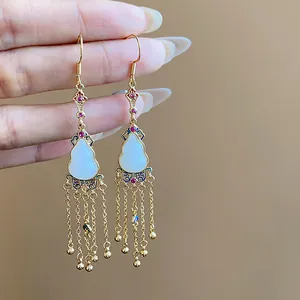 Detail of 14K gold plated vintage gourd earrings featuring delicate chain tassels and red gems.
