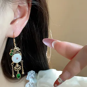 Close-up of 14K gold plated vintage Chinese style earrings with white stone and green gems
