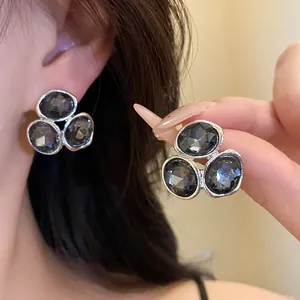 Close-up of elegant smoke grey crystal earrings with steel needles in a silver frame.