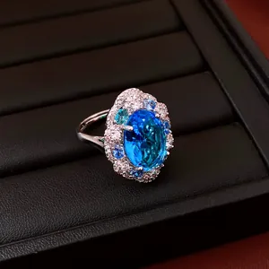 Detailed close-up of a sparkling oval blue zircon ring with a halo of accent stones