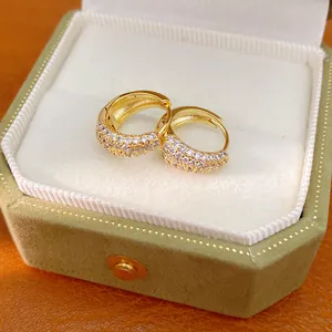 Detailed close-up of 14K gold plated zircon hoop earrings in an olive green velvet box