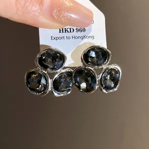 Close-up of elegant silver-tone earrings featuring multifaceted grey crystal cluster