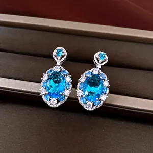 Close-up view of elegant oval blue zircon earrings with a sparkling halo design