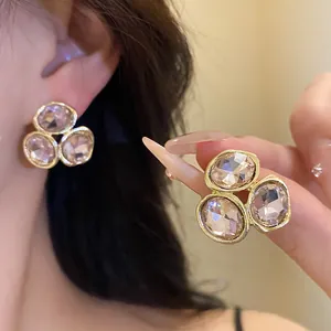 Detailed close-up of elegant gold stud earrings with three clustered champagne crystals