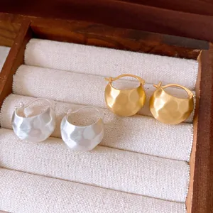 Nahaufnahme von eleganten gebürsteten halbkreisförmigen Creolen in Gold und Silber
