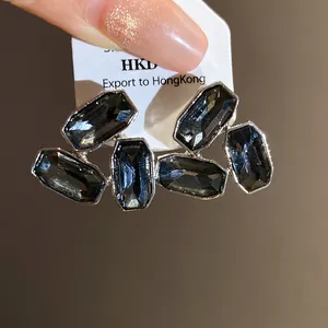 Detailed close-up view of geometric dark crystal stud earrings with rectangular facets.
