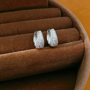 Macro detail of pavé zircon hoop earrings displayed on a brown velvet jewelry tray