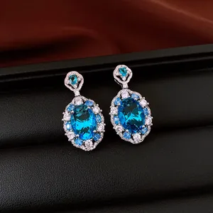 Close-up of elegant sparkling oval blue zircon drop earrings with halo stones on a black display