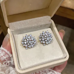 Primo piano di orecchini a perno tondi color argento con zirconi in una confezione.