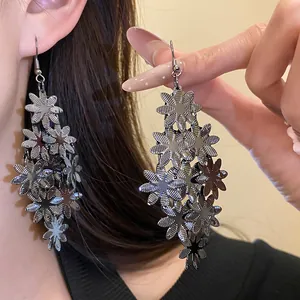 Dettaglio di orecchini pendenti a nappa di fiori metallici che mostrano il design dei petali.